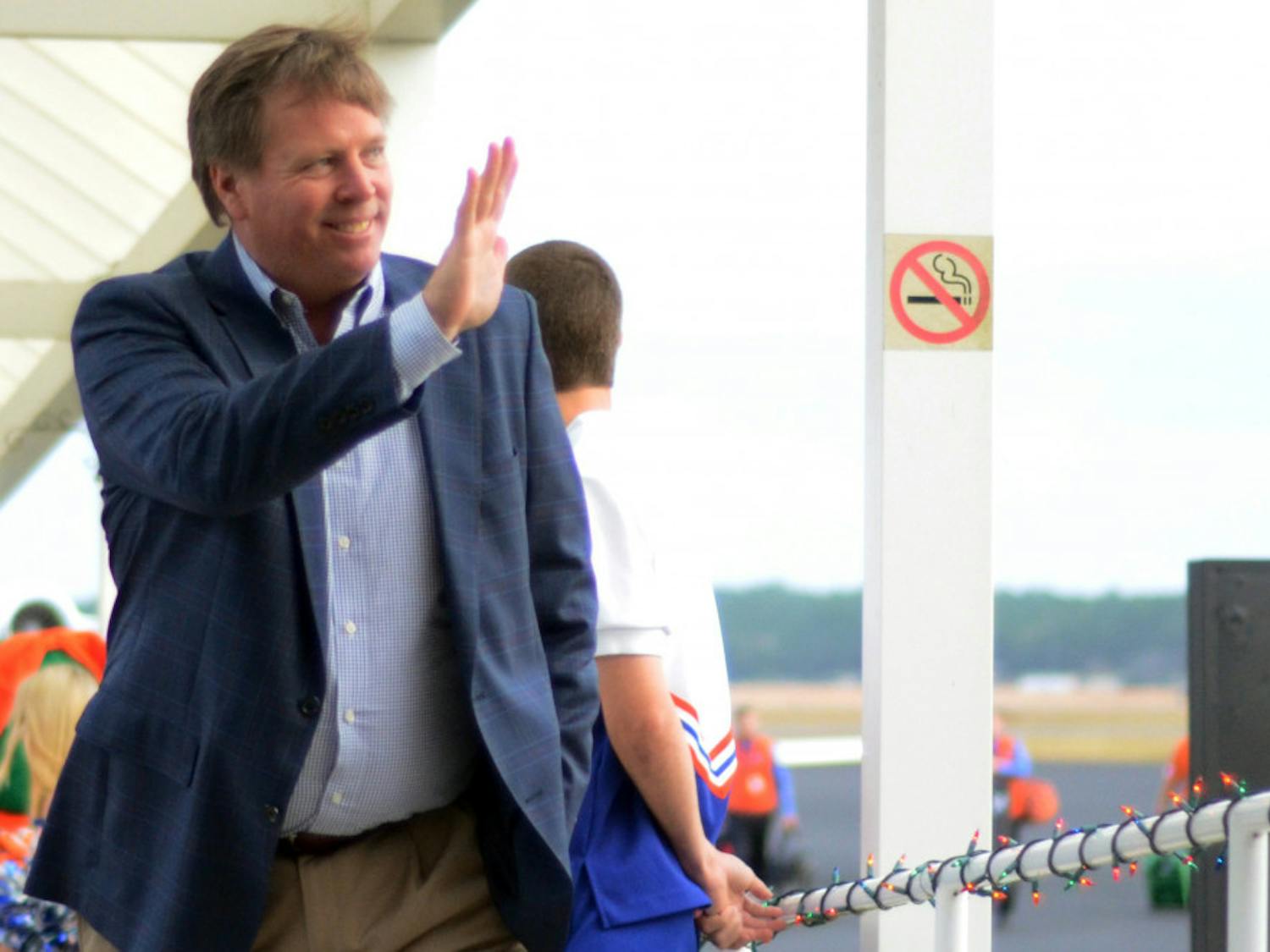 Jim McElwain waves as he walks off the plane after arriving in Gainesville on Dec. 5, 2014.