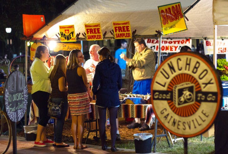Gainesville residents gather around a vendor's booth near the Lunch Box during the Union Street Farmers Market Wednesday evening.