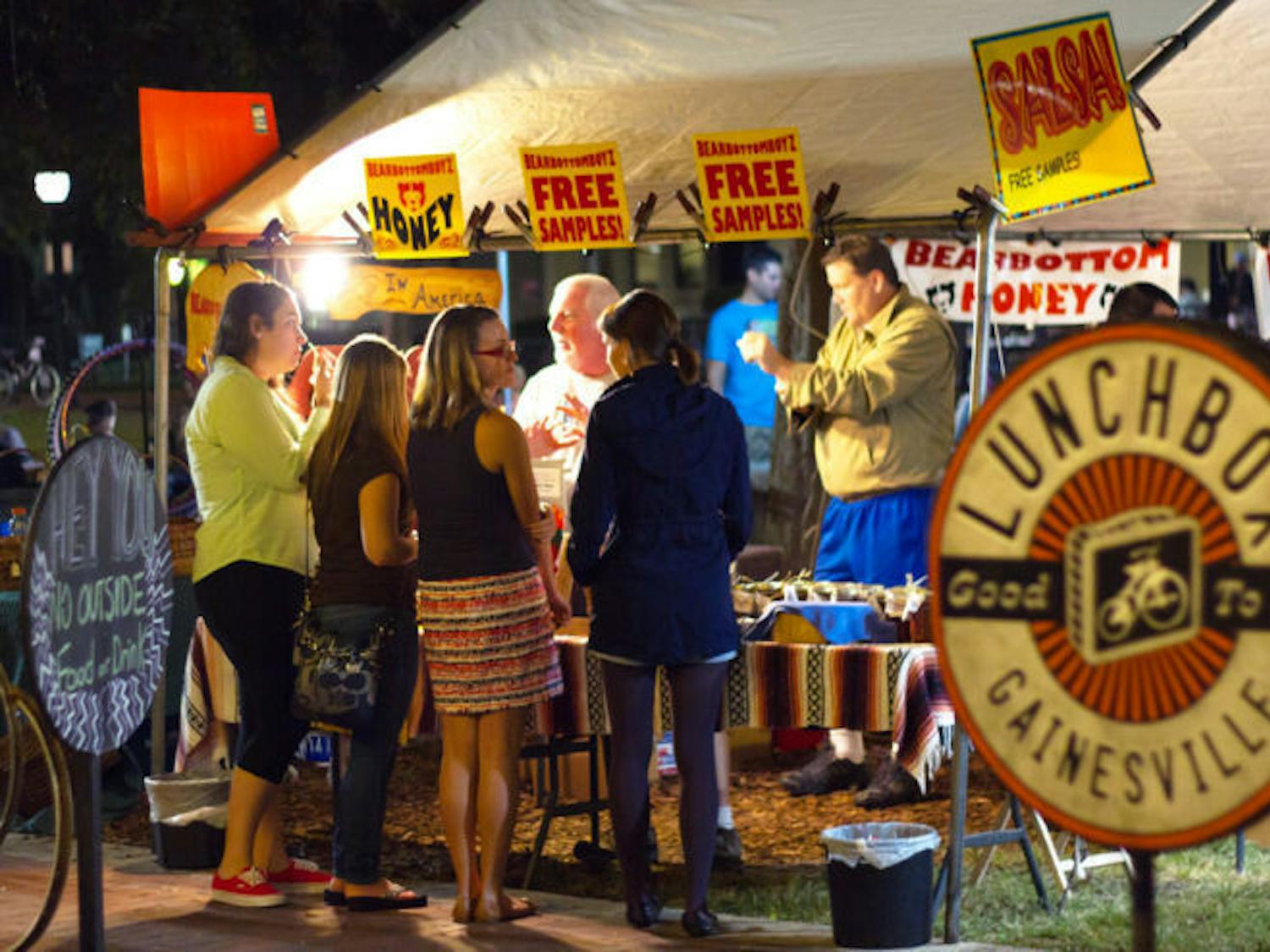 Gainesville residents gather around a vendor's booth near the Lunch Box during the Union Street Farmers Market Wednesday evening.