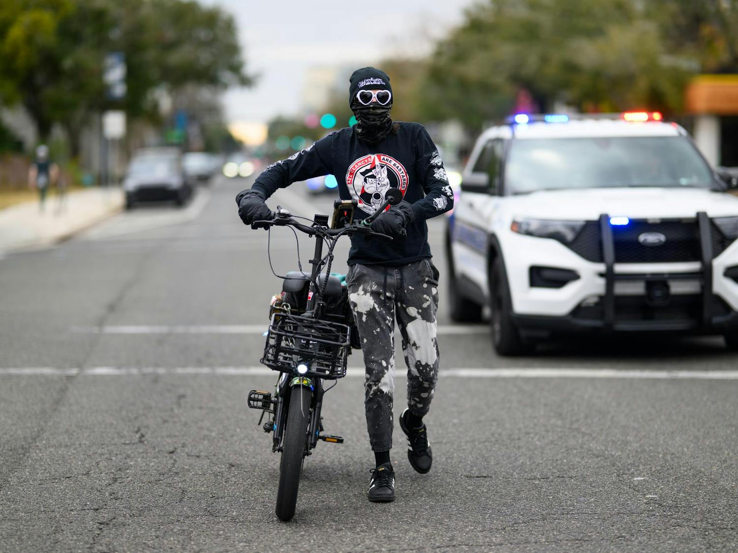 A masked man with a bike and speaker approaches demonstrators during an ICE protest organized by YDSA, Friday, Jan. 30, 2026, along University Avenue in Gainesville, Fla.