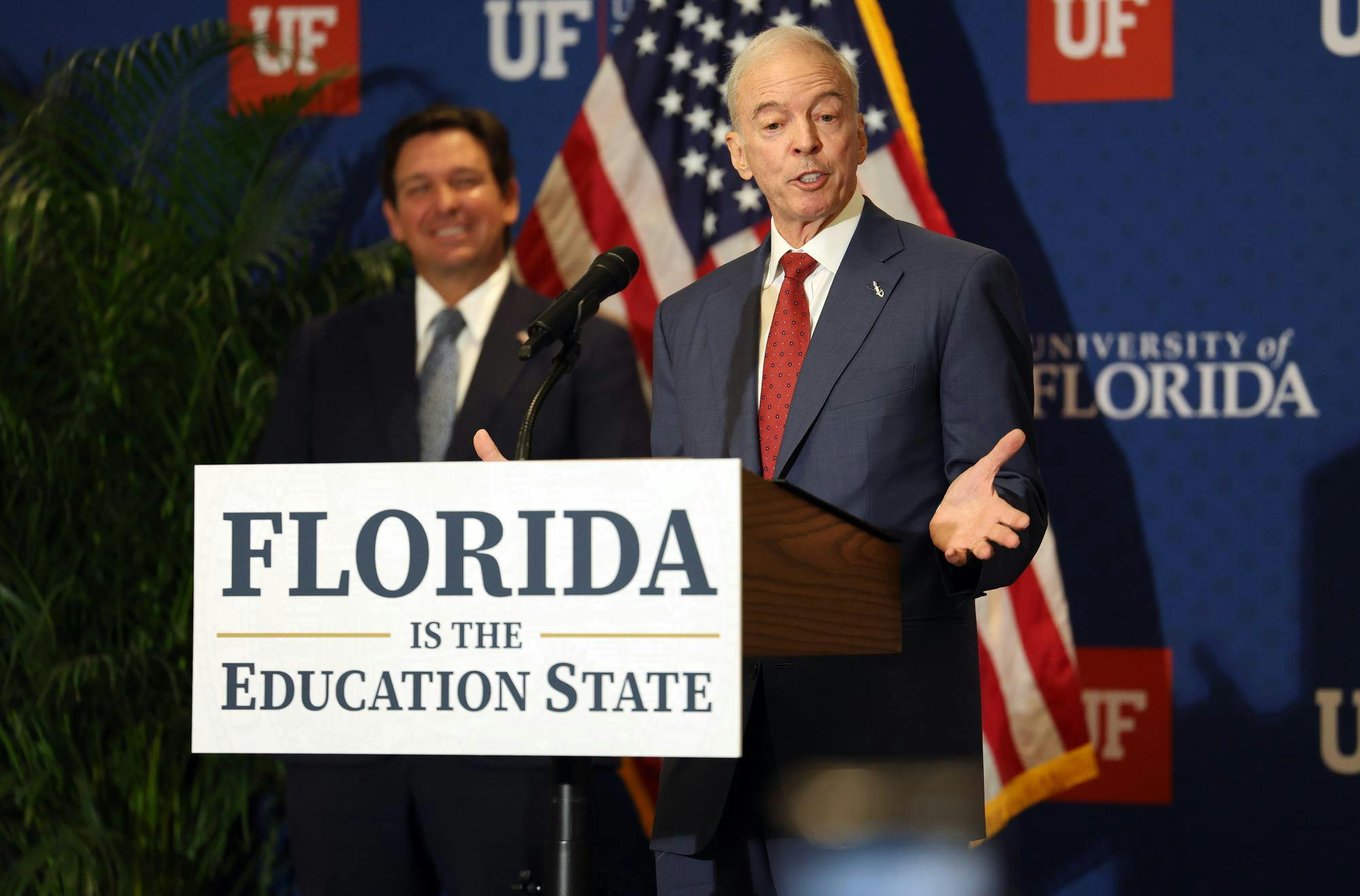 Interim University of Florida President Dr. Donald Landry speaks as Gov. Ron DeSantis smiles in the background at Emerson Alumni Hall on the university’s campus on Monday, Sept. 29, 2025.