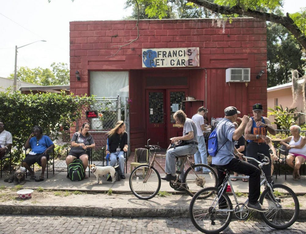 Owners and their pets sit outside the current St. Francis Pet Care clinic, located at 501 SE Second St., while they wait to be seen.