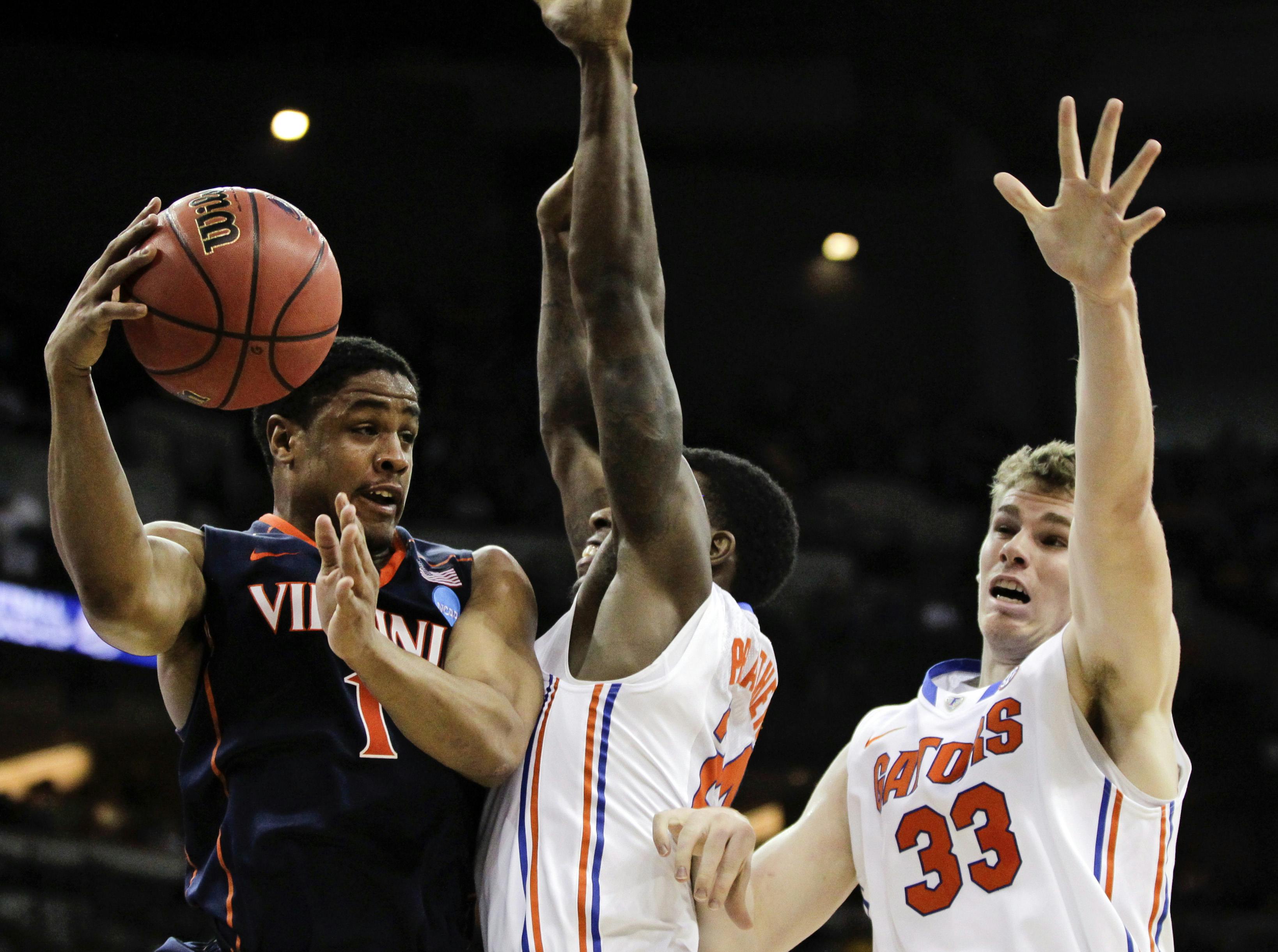 Virginia's Jontel Evans, left, passes around the defense of Florida's Casey Prather and Erik Murphy (33) during the first half of an NCAA tournament second-round college basketball game at CenturyLink Center in Omaha, Neb., Friday, March 16, 2012.