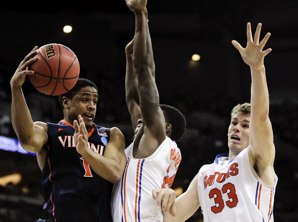 <p>Virginia's Jontel Evans, left, passes around the defense of Florida's Casey Prather and Erik Murphy (33) during the first half of an NCAA tournament second-round college basketball game at CenturyLink Center in Omaha, Neb., Friday, March 16, 2012.</p>