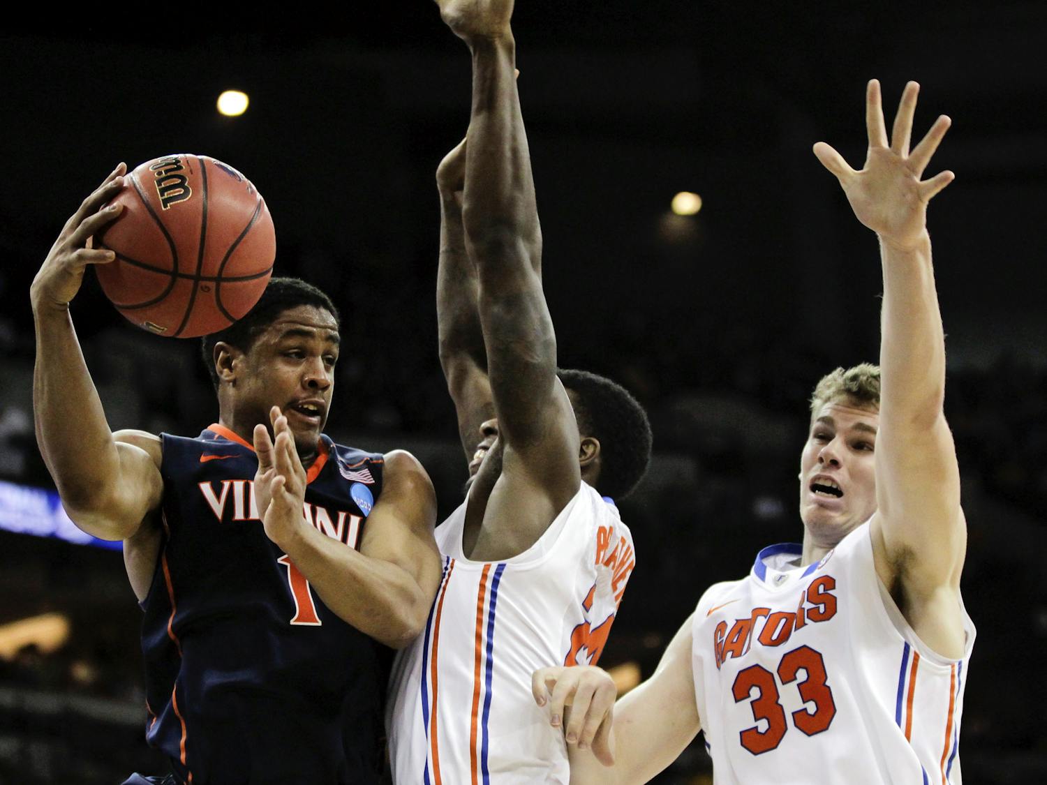 Virginia's Jontel Evans, left, passes around the defense of Florida's Casey Prather and Erik Murphy (33) during the first half of an NCAA tournament second-round college basketball game at CenturyLink Center in Omaha, Neb., Friday, March 16, 2012.