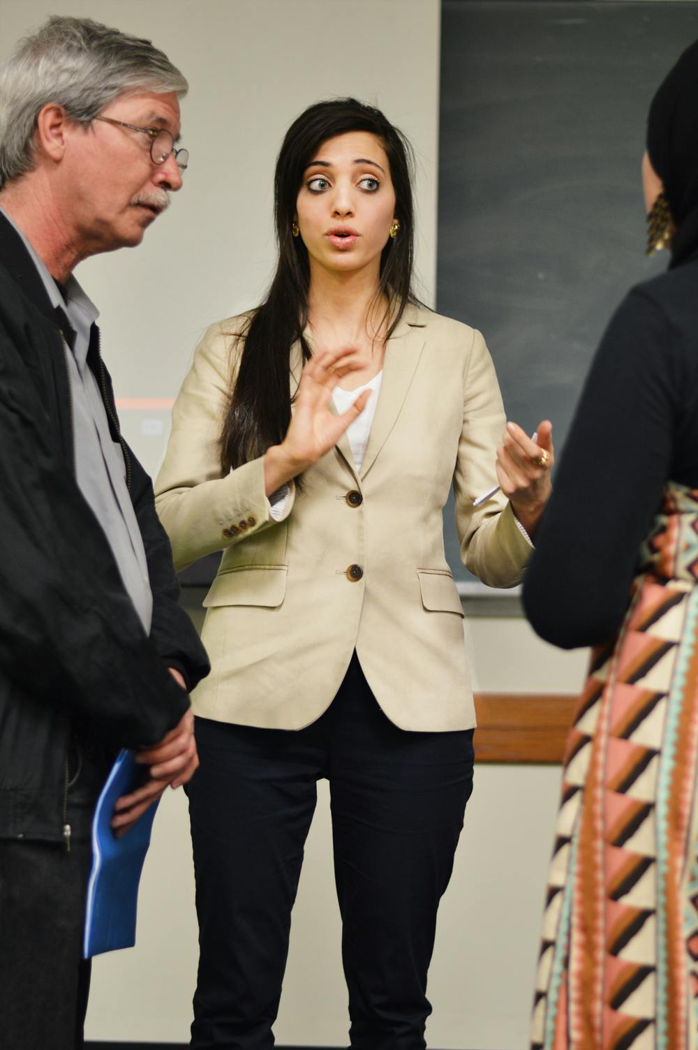 <p>Mick Kelly, left, listens while Noor Elashi, center, discusses the itinerary with Sara Mohamed on Tuesday evening in Little Hall.</p>