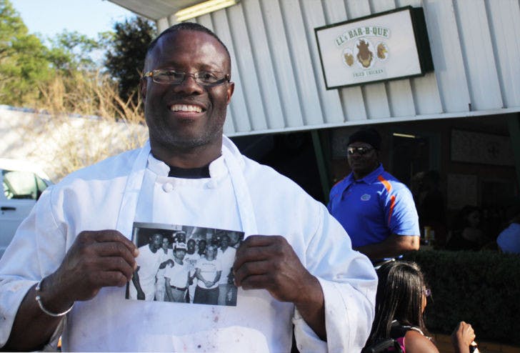Louis Lee stands in front of his new restaurant, LL’s Bar-B-Que, at 3807 E. University Ave., holding a photo of himself when he first started working as the Pi Lambda Phi chef.