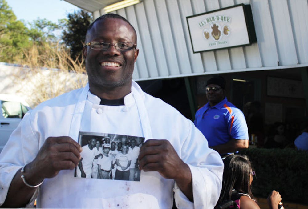 <p>Louis Lee stands in front of his new restaurant, LL’s Bar-B-Que, at 3807 E. University Ave., holding a photo of himself when he first started working as the Pi Lambda Phi chef.</p>