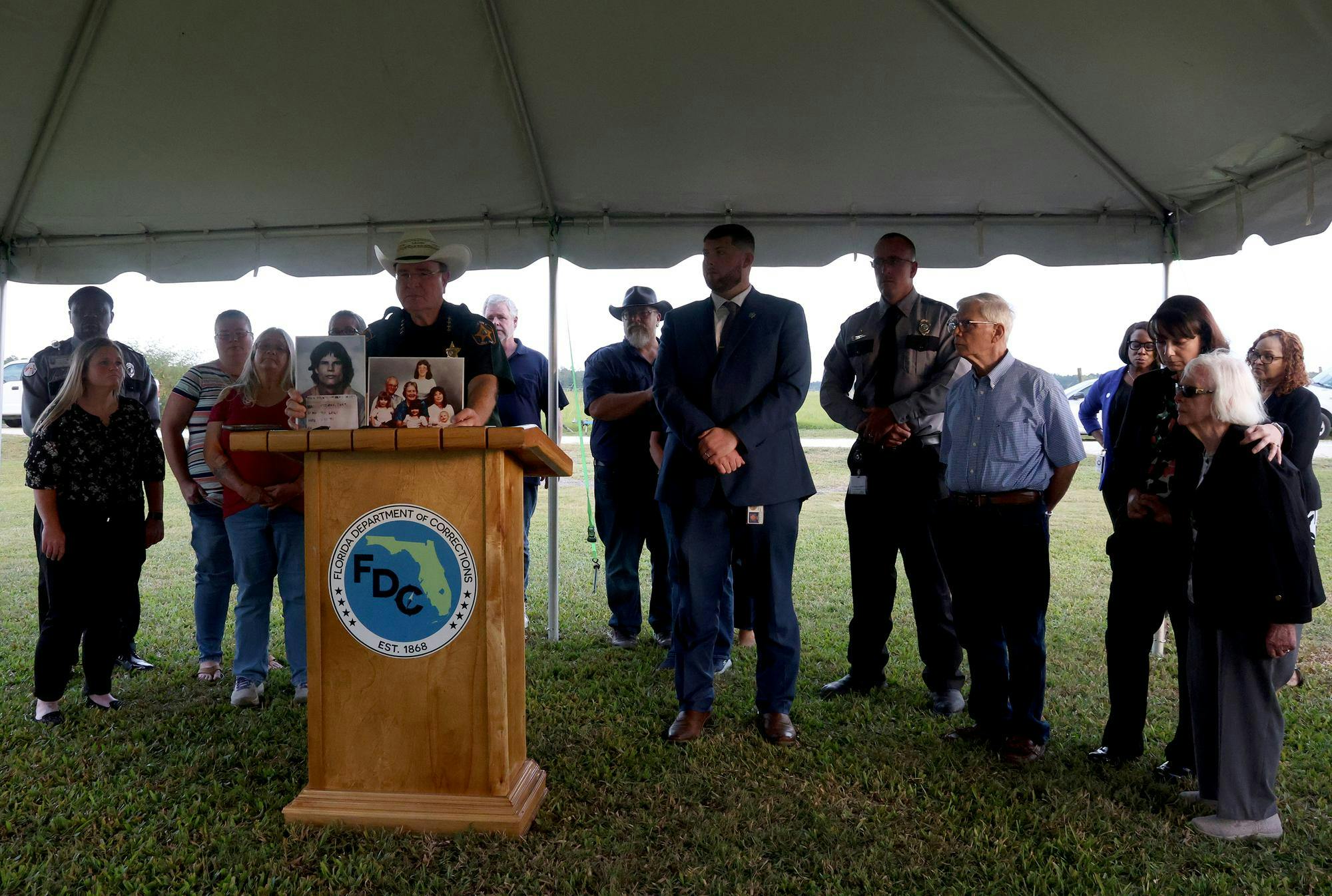 Polk County Sheriff Grady Judd holds up the mugshot of David Pittman, who was executed, and the Knowles family, whom Pittman victimized, while surrounded by members of the Knowles family. The execution was carried out at Florida State Prison on Wednesday, Sept. 17, 2025. 