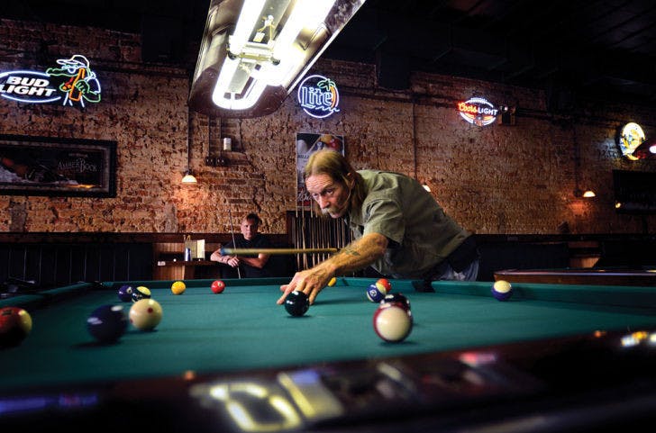 “Doctor” Robert Ramsthaler takes a shot during a game of pool as Tom Miller, the first official billiard therapy patient, watches Sept. 16 at Main Street Bar &amp; Billiards.