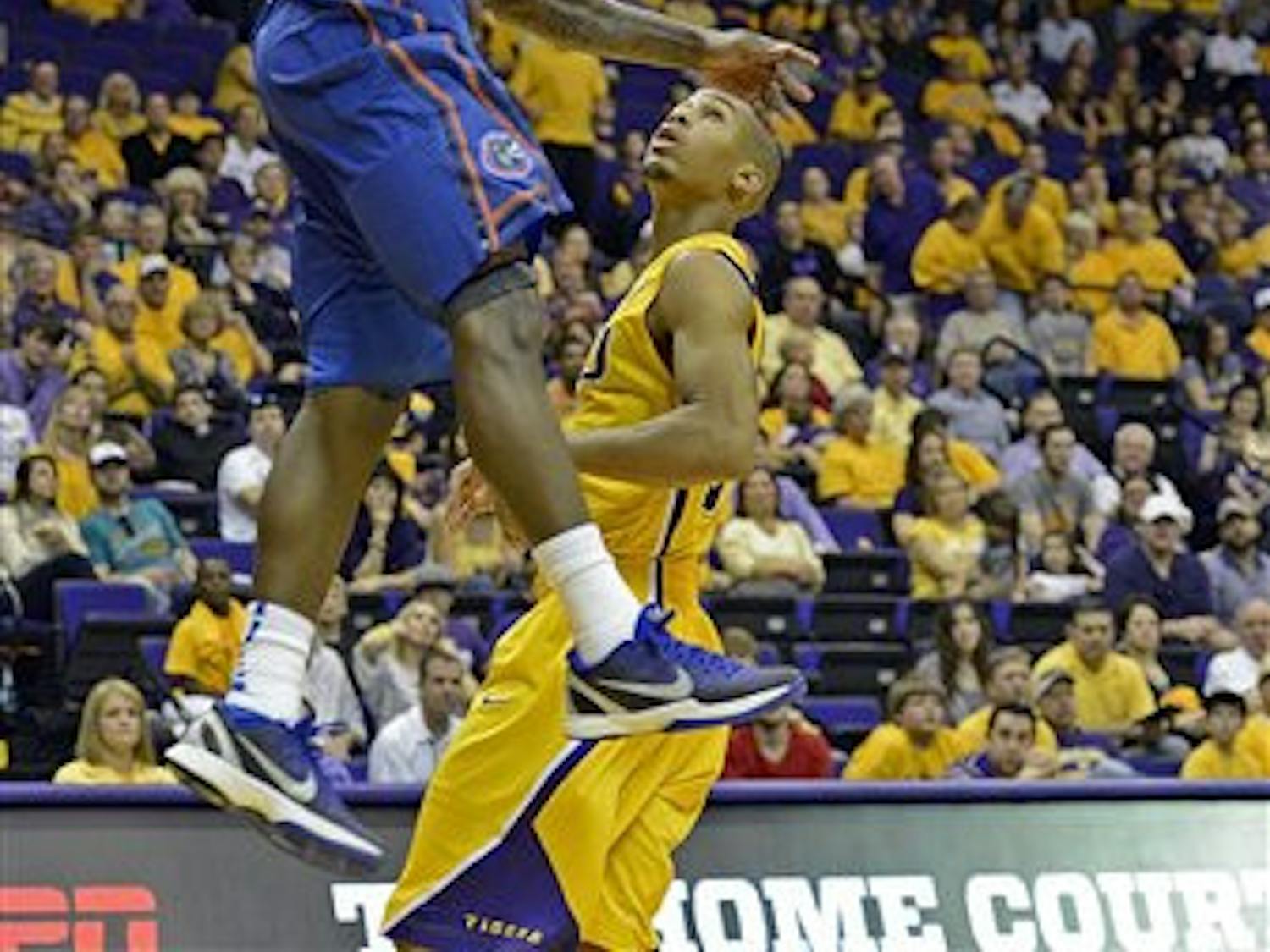 Florida guard Kenny Boynton, top, dunks the ball in front of LSU guard Charles Carmouche during the second half of an NCAA college basketball game at the Pete Maravich Assembly Center in Baton Rouge, La., Saturday, Jan. 12, 2013. Florida won 74-52.(AP Photo/Bill Feig)