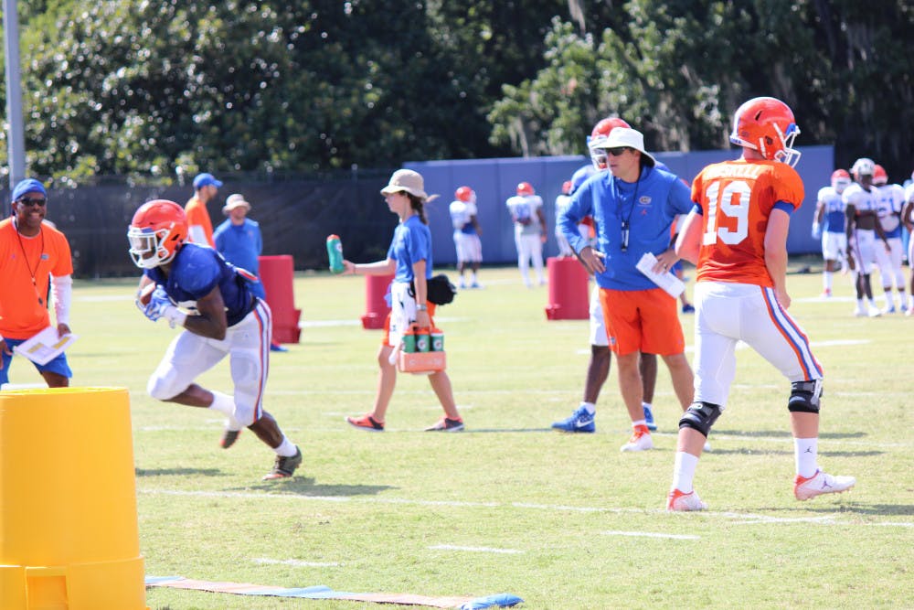 Coach Dan Mullen (right) evaluates his quarterbacks and running backs during fall camp. At Monday's press conference, he said he'll be evaluating the starting quarterback contenders over the next couple of days. 
