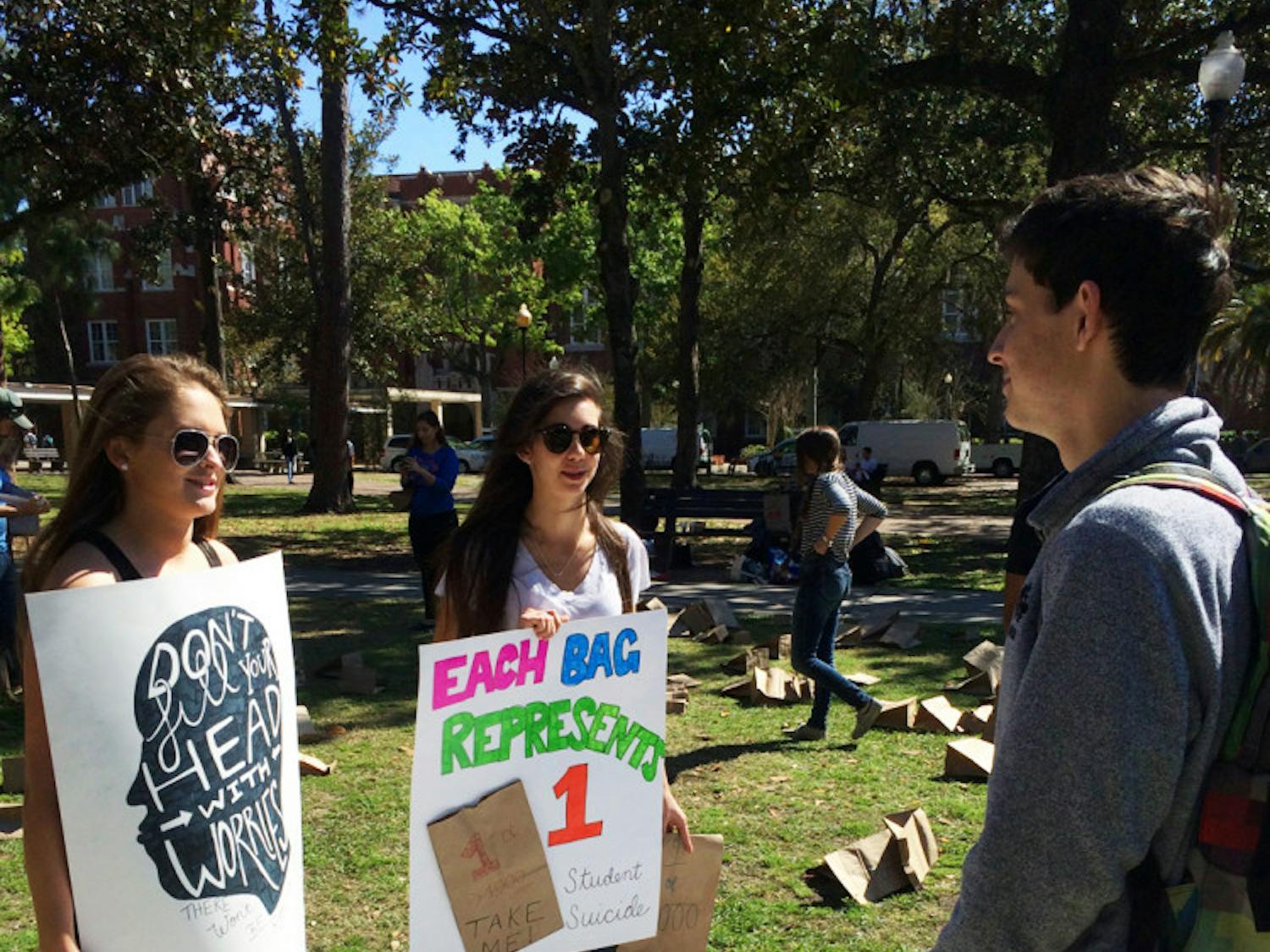 Michelle Smith, a 20-year-old UF health science sophomore, and Christine Marino, a 21-year-old UF health education and behavior junior, talk to Joseph Buss, a 19-year-old UF economics sophomore, during Alpha Epsilon Delta’s “Every Gator Counts” event. The pre-health honor society passed out 400 paper bags holding anonymous stories of AED members’ struggles with mental illness to let students know they’re not alone.