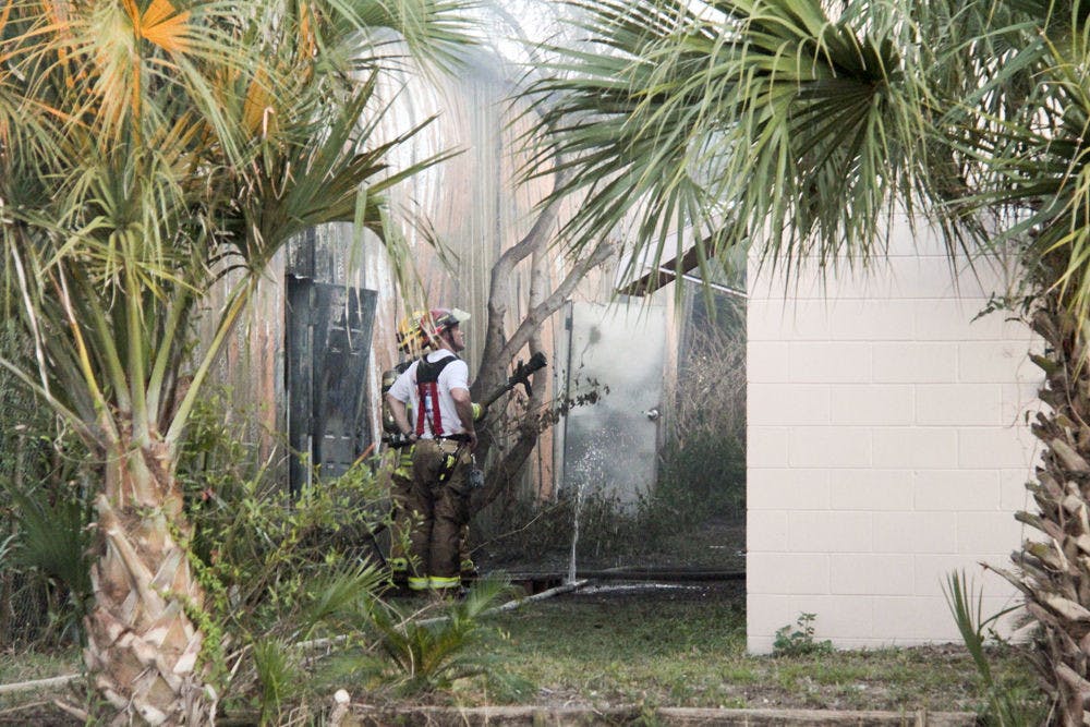 <p class="p1"><span class="s1">Gainesville Fire Rescue Lt. D.G. Campbell Jr. stands with another firefighter as he sprays water on a building neighboring Mica-Mode Cabinetry that caught fire at about 4 p.m. Wednesday. No one was injured in the fire, according to Gainesville Fire Rescue Assistant Chief JoAnne Rice.</span></p>