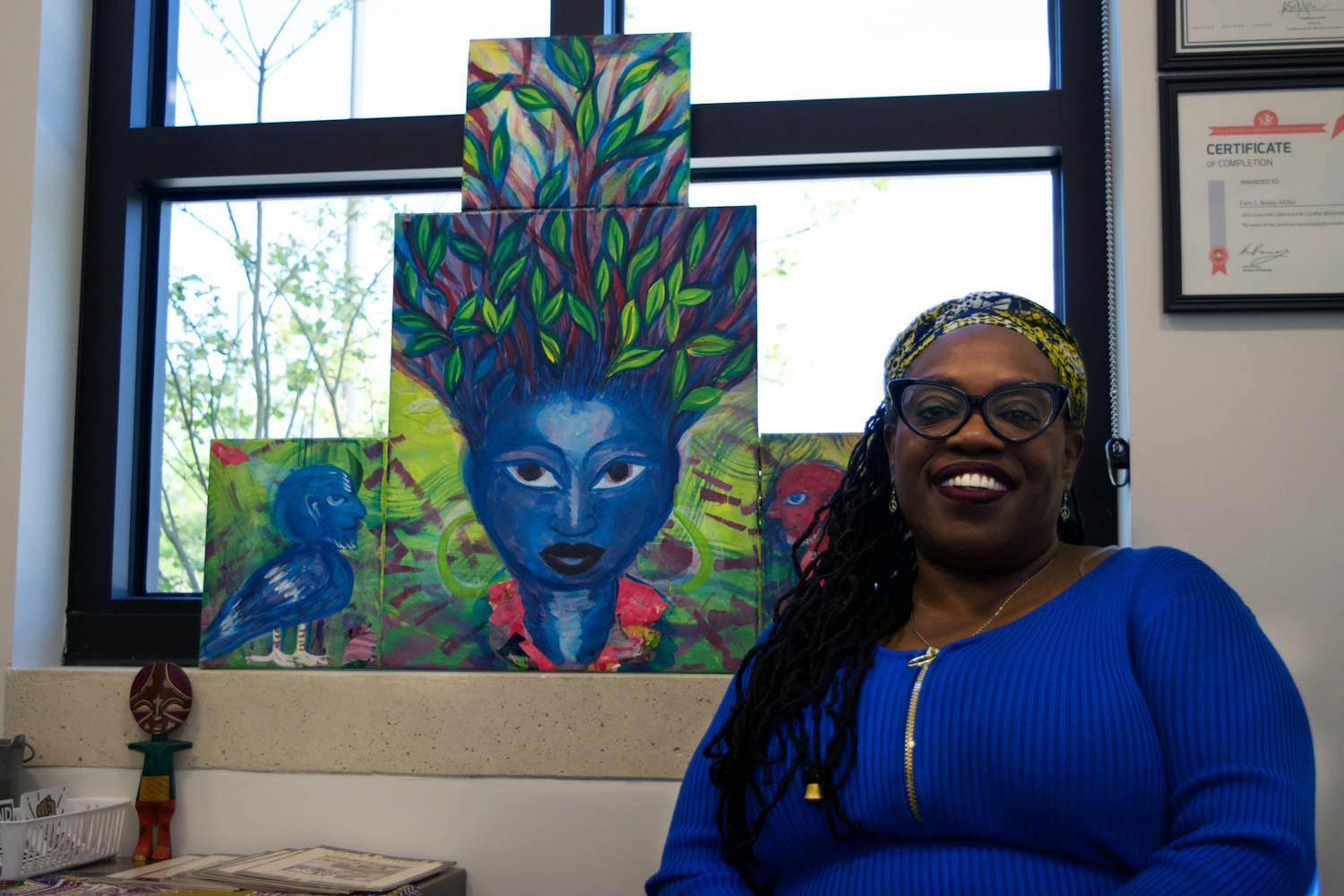 Terri Bailey sits in front of “Iya,” a painting created by Turbado Marabou, in Blount Hall Sunday, March 18, 2023.