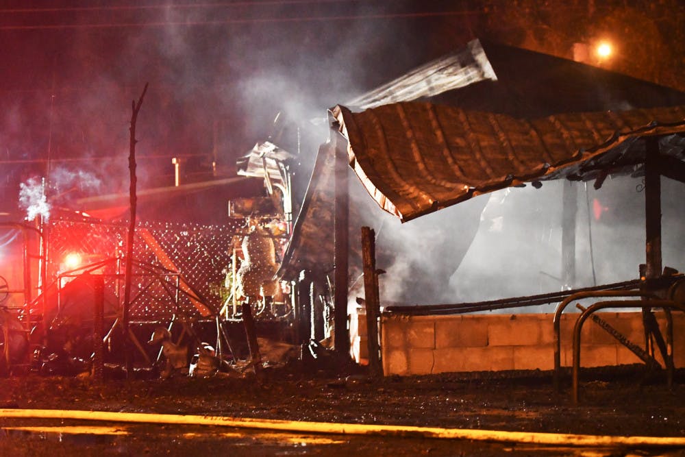 The tin roof of Lightnin’ Salvage sits in pieces as firefighters search the area for hotspots on Monday evening. The main dining room was not touched by the fire.