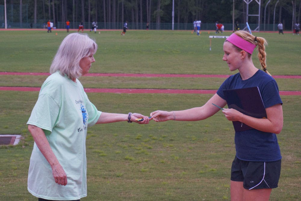 Margaret Hazlett, a 23-year-old UF doctoral candidate, gives Diane David an ice pop stick as she completes a lap around the track at Fred Cone Park at the Walktober Wellness Walk on Monday evening.