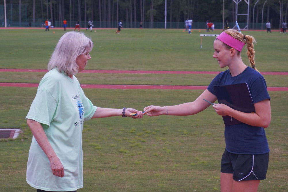 <p class="p1">Margaret Hazlett, a 23-year-old UF doctoral candidate, gives Diane David an ice pop stick as she completes a lap around the track at Fred Cone Park at the Walktober Wellness Walk on Monday evening.</p>