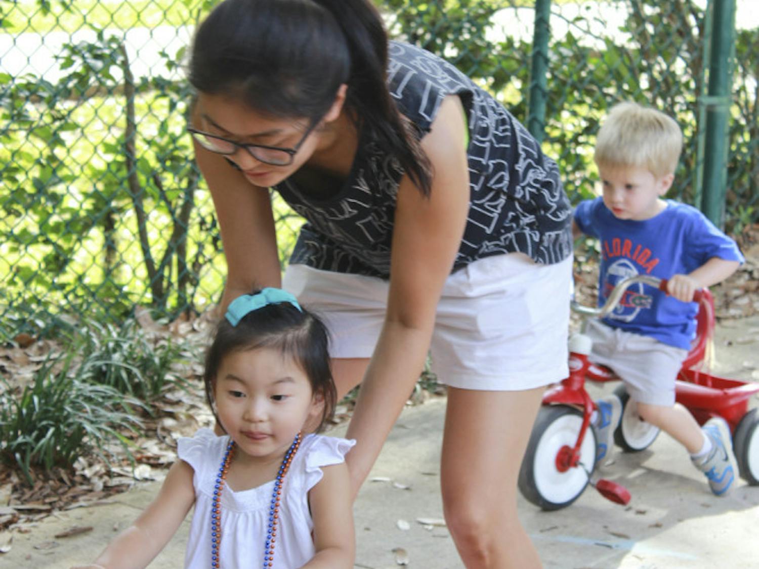 Former UF PhD student Soon Hye Yang, 34, pushes her 3-year-old daughter, Isu Yoon, on a tricycle at the Baby Gator daycare center on Nov. 5, 2015. Baby Gator’s request for additional funding was denied, and without it, student parents like Yang may be cut from the program.