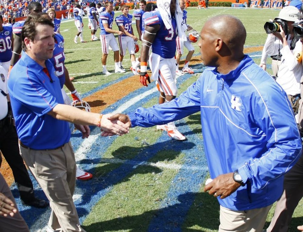 <p>Gators coach Will Muschamp shakes hands with Kentucky coach Joker Phillips after the game at Ben Hill Griffin Stadium on Saturday. Kentucky moved to 23-57 in conference play since 2002.</p>