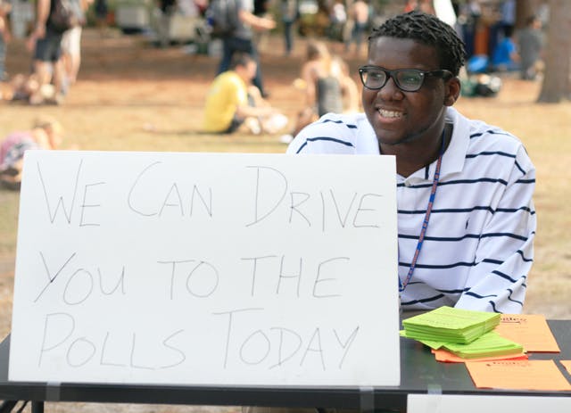 Eric Brown, 18-year-old political science freshman, promotes Students for a Democratic Society's free rides to early voting on Wednesday afternoon on the Plaza of the Americas.