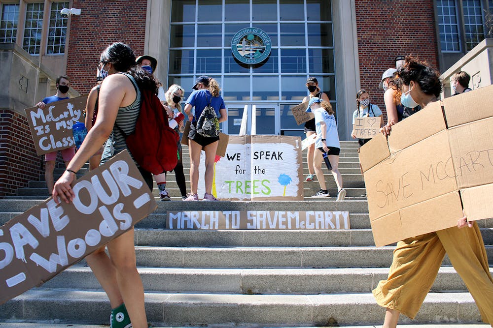 Participants in the "March to Save McCarty" place signs on the steps of the UF Administration building on Saturday, March 13, 2021. The march was held to raise awareness about McCarty Woods' potential designation as a future construction site, which UF has since rescinded. 