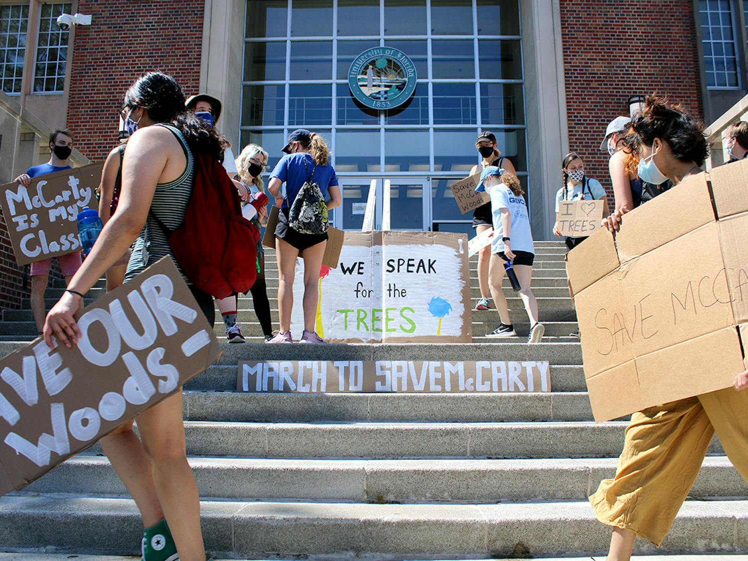 Participants in the "March to Save McCarty" place signs on the steps of the UF Administration building on Saturday, March 13, 2021. The march was held to raise awareness about McCarty Woods' potential designation as a future construction site, which UF has since rescinded.