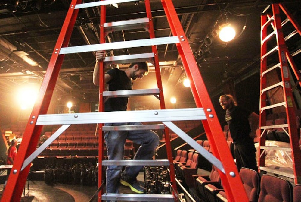 <p>Josh Allen, 27, (left) and Nelson Isaac, 41, (right) work on lighting for the upcoming show “Carrie” at the Hippodrome State Theatre on Monday.</p>