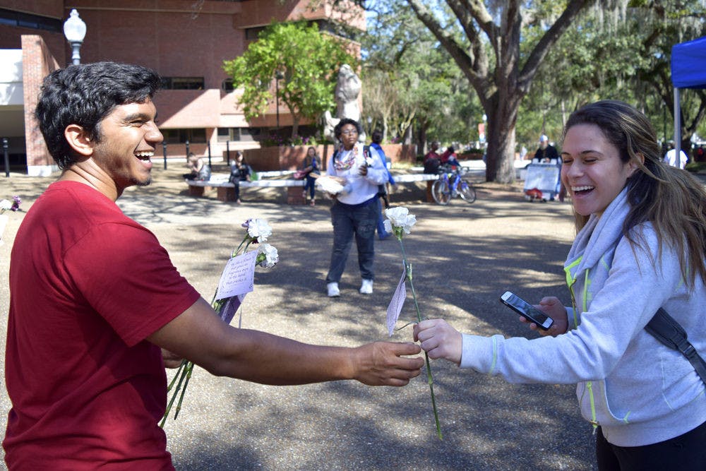 Dylan Diljohn (left), 21, gives a flower to Chelsey Perez, 22, at Turlington Plaza on Wednesday morning. Diljohn, a fourth-year UF microbiology student, said he hopes to raise awareness of Islam Appreciation Month on behalf of Islam On Campus.