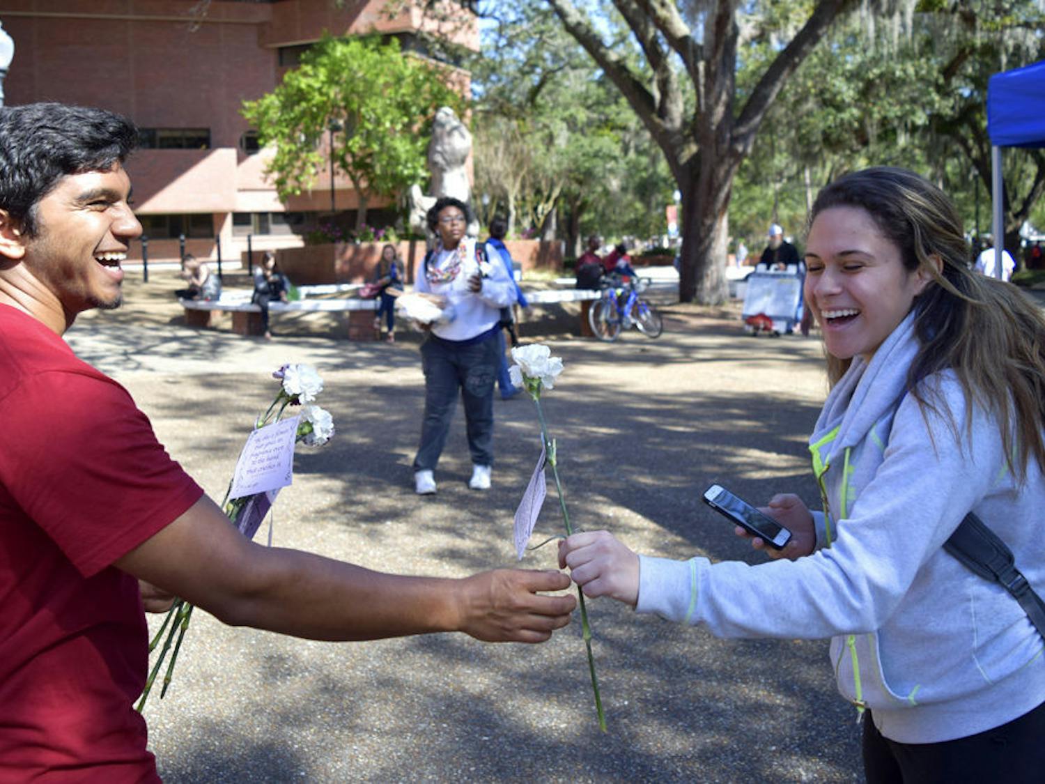 Dylan Diljohn (left), 21, gives a flower to Chelsey Perez, 22, at Turlington Plaza on Wednesday morning. Diljohn, a fourth-year UF microbiology student, said he hopes to raise awareness of Islam Appreciation Month on behalf of Islam On Campus.