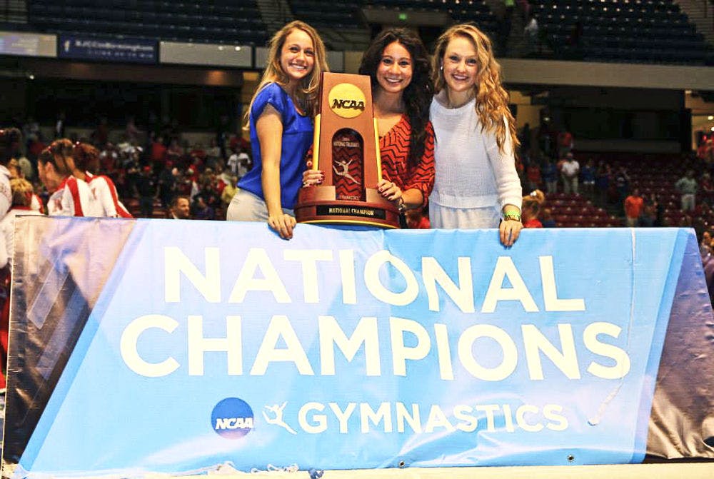 UF alumna and former Gator gymnast Marissa King (center) holds the 2014 National Championship trophy as the assistant coach. King joined the Cirque du Soleil Amaluna tour Friday and will begin performing this coming weekend.