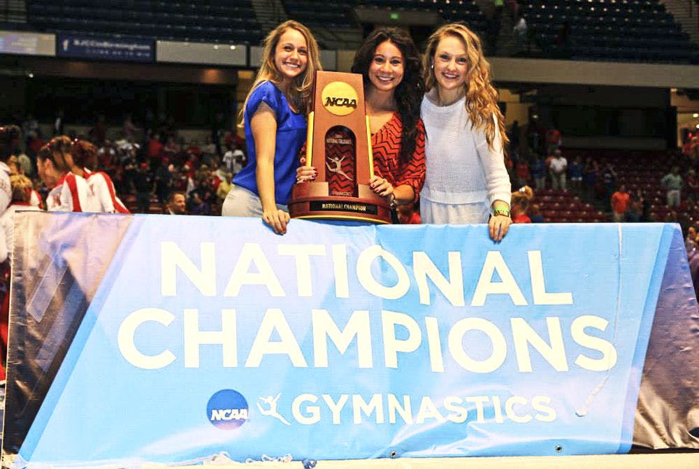 <p class="p1">UF alumna and former Gator gymnast Marissa King (center) holds the 2014 National Championship trophy as the assistant coach. King joined the Cirque du Soleil Amaluna tour Friday and will begin performing this coming weekend.</p>