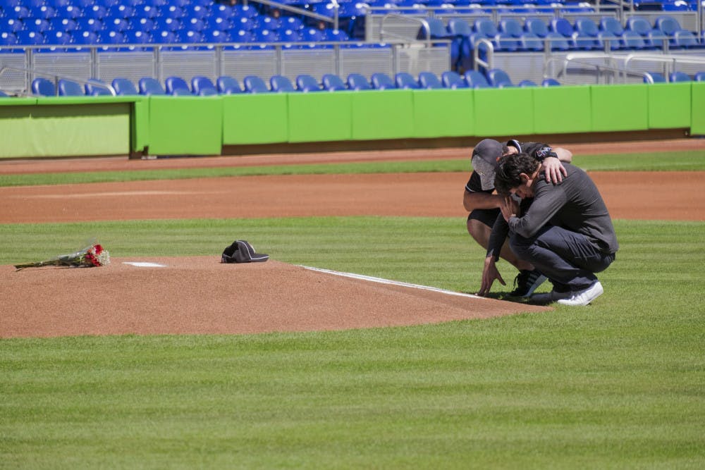 Miami Marlins player Christian Yelich, right, and teammate Justin Bour react in front of a memorial on the pitcher's mound at Marlins Park for Marlins pitcher Jose Fernanedez, Sunday, Sept. 25, 2016 in Miami. Fernandez, the ace right-hander for the Miami Marlins who escaped Cuba to become one of baseball's brightest stars, was killed in a boating accident early Sunday morning. The game between the Marlins and the Atlanta Braves was cancelled.