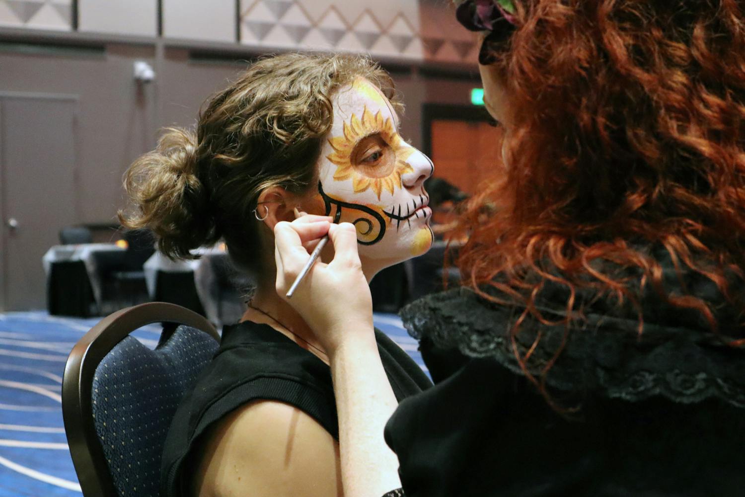 Eryn Brazlavsky gets her face painted by Haley Damon at the MASA Día de los Muertos celebration Wednesday, Nov. 2, 2022.