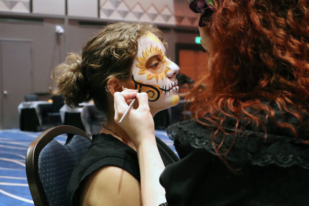 <p>Eryn Brazlavsky gets her face painted by Haley Damon at the MASA Día de los Muertos celebration Wednesday, Nov. 2, 2022.</p>