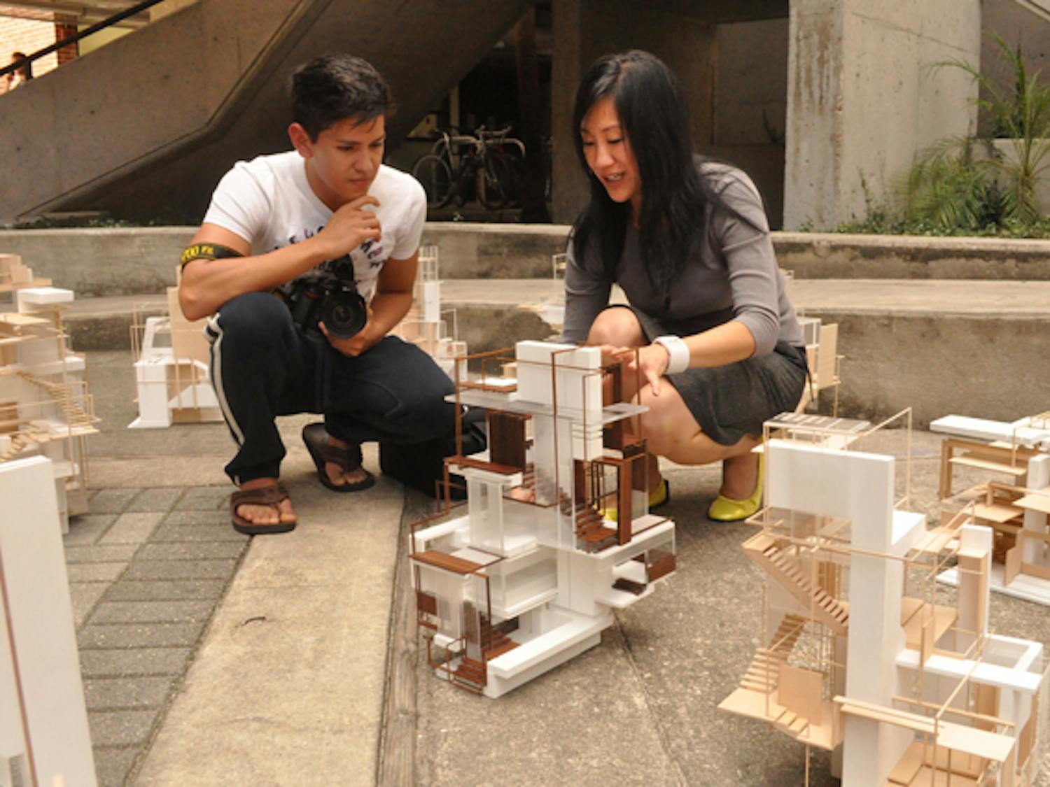 Lisa Huang, a design 3 professor, critiques the work of Daniel Izquierdo, a 19-year-old design 3 architecture major, at the Door Window Stair&nbsp;show in the atrium of the Architecture Building on Friday. It was Izquierdo's personal choice to use a linseed oil finish on the wood in his project to add a contrast to the white paper.&nbsp;