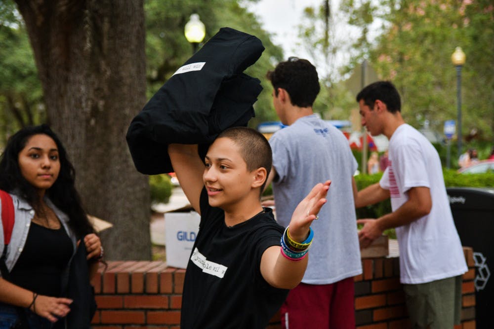Emma Gonzalez, a 18-year-old Stoneman Douglas Graduate, throws shirts to UF students Monday night at Turlington Plaza. Gonzalez is a member of the National March For Our Lives team who coordinated the event with March For Our Lives Gainesville to get students to vote in the upcoming election.  