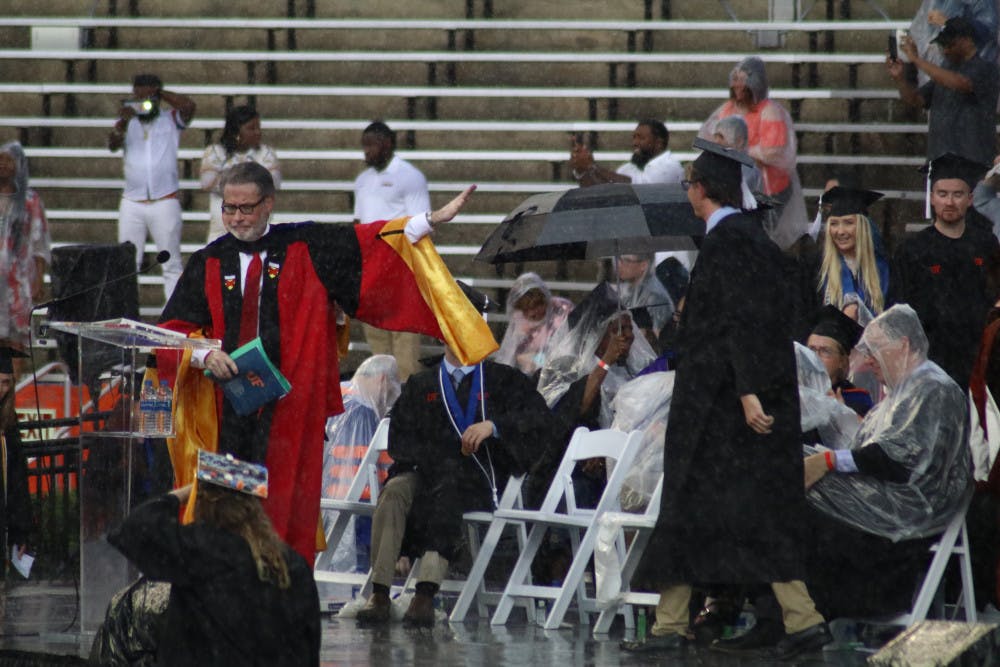 College of Liberal Arts and Sciences Dean, David Richardson, gestures to pause the commencement ceremony. Richardson announced the ceremony would be delayed by 30 minutes, but the ceremony was later moved to an insidehallway of the stadium.