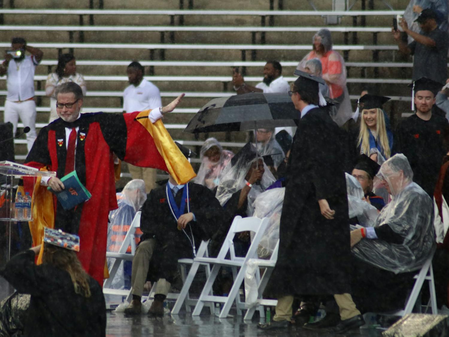 College of Liberal Arts and Sciences Dean, David Richardson, gestures to pause the commencement ceremony. Richardson announced the ceremony would be delayed by 30 minutes, but the ceremony was later moved to an insidehallway of the stadium.