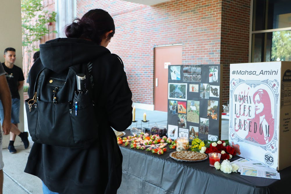 <p>Marium Abdulhussein, 19, quietly recites Islamic funeral passages to the memorial of Mahsa Amini, Thursday, Sept. 22, 2022. Abdulhussein is a third-year student at UF.</p>