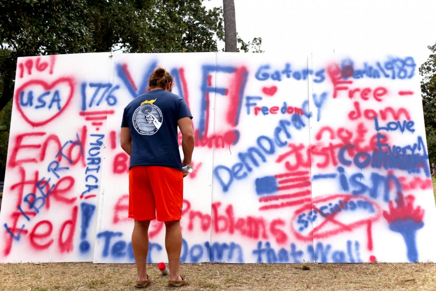 Daniel Weldon, a 20-year-old UF political science sophomore and the president of Young Americans for Freedom, stands in front of a commemorative wall for the anniversary of the fall of the Berlin Wall on the Plaza of the Americas on Wednesday afternoon. Weldon said the event celebrated the triumph of freedom from socialism.