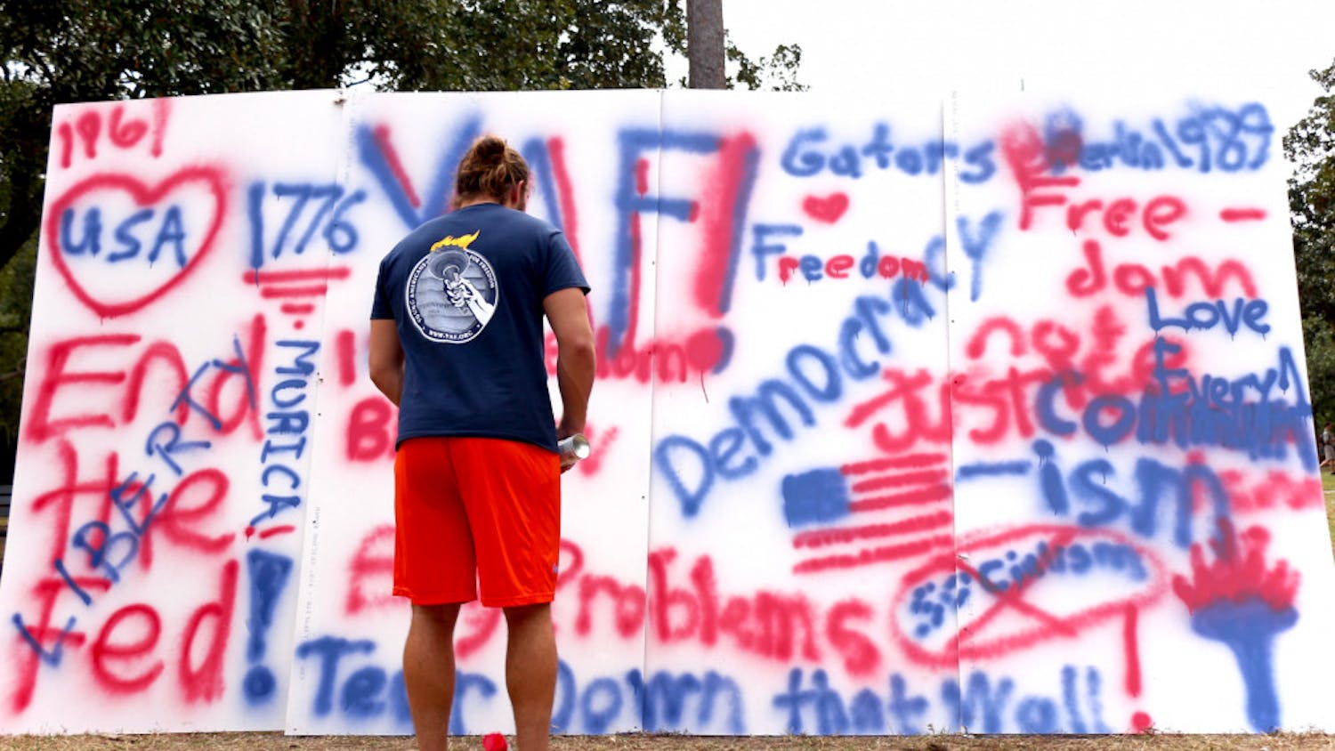 Daniel Weldon, a 20-year-old UF political science sophomore and the president of Young Americans for Freedom, stands in front of a commemorative wall for the anniversary of the fall of the Berlin Wall on the Plaza of the Americas on Wednesday afternoon. Weldon said the event celebrated the triumph of freedom from socialism.