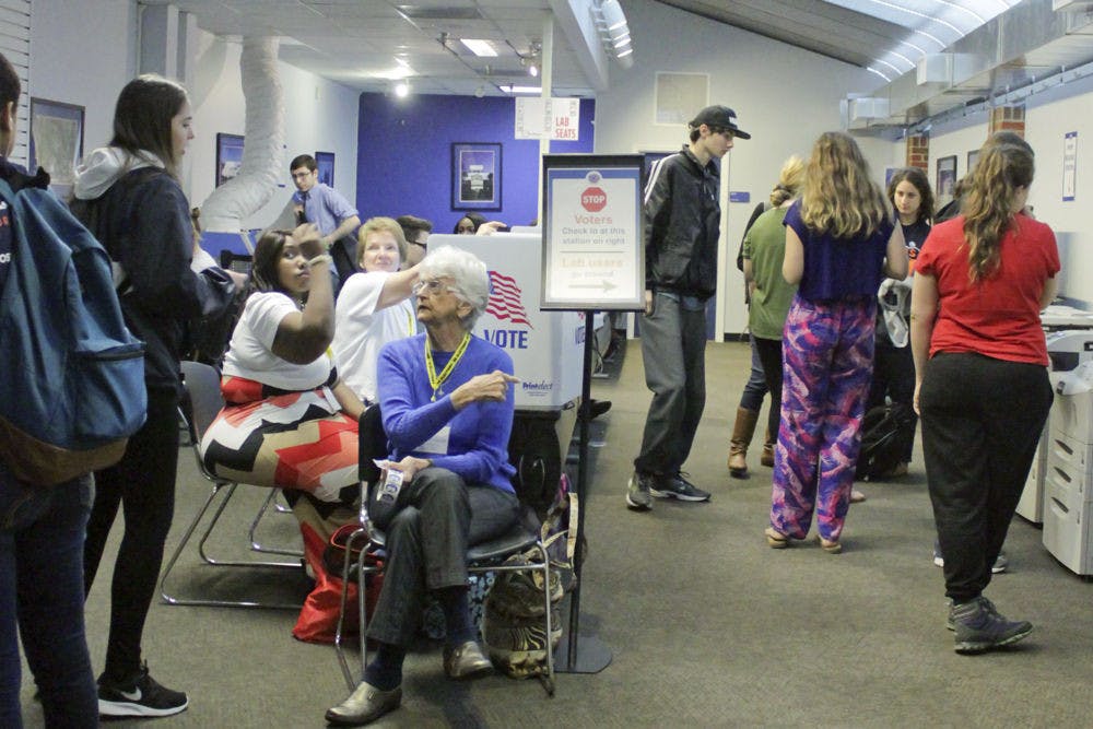 <p>Kathy Bolton (center), a Gainesville poll worker, helps direct students and hands out "I voted" stickers in the Reitz Union computer lab Tuesday. UF students can vote in Student Government elections until 8:30 p.m. today.</p>