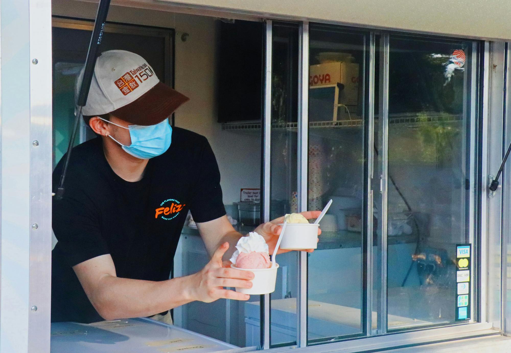 Ryan Ealy, 20, Feliz Flavors shift lead, hands off two small ice creams to customers on Sunday, Sept. 5, 2021. The truck is located at 4th Ave Food Park and has flavors that range from matcha to passion fruit. 