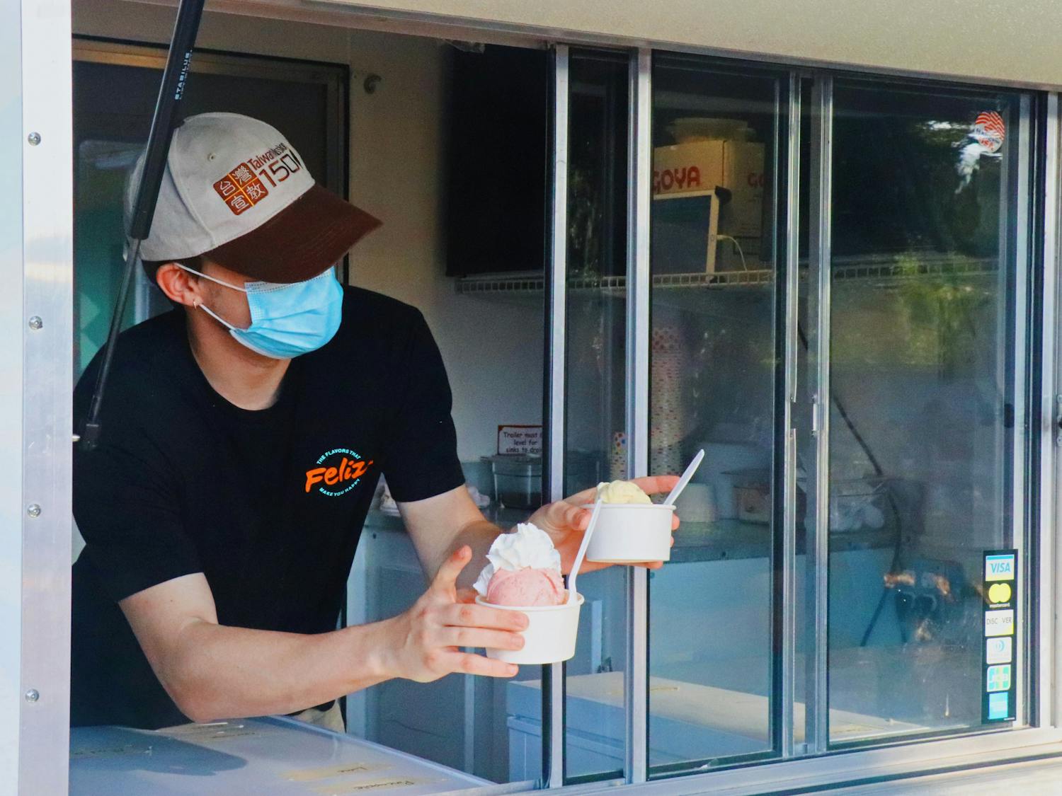 Ryan Ealy, 20, Feliz Flavors shift lead, hands off two small ice creams to customers on Sunday, Sept. 5, 2021. The truck is located at 4th Ave Food Park and has flavors that range from matcha to passion fruit.