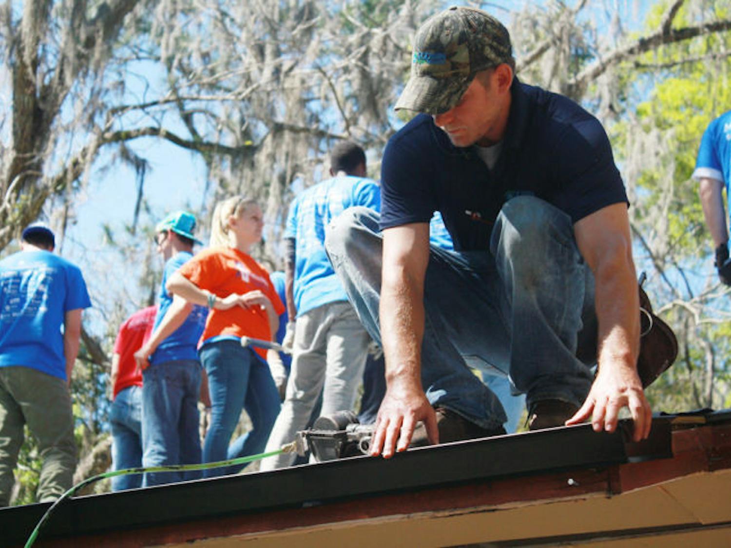 Students and professors with Rebuilding Together North Central Florida help rebuild a Waldo homeowner’s roof on Thursday. Chanita Ross is a widow and needed the help so she could keep living in her home.