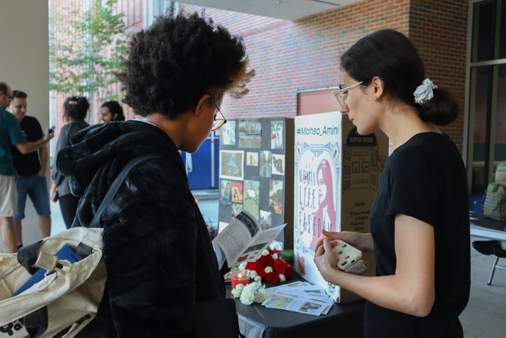 <p>A member of the Iranian Student Association passes an educational brochure about Mahsa Amini’s death and Iranian hijab laws to a passerby, Thursday, Sept. 22, 2022.</p>