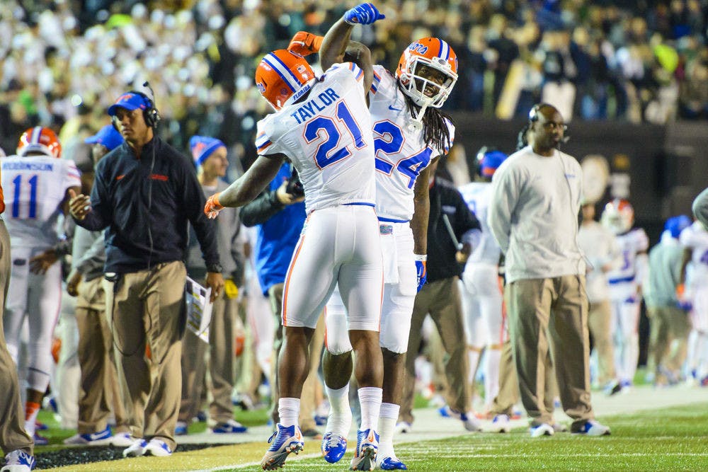 <p>Florida running back Kelvin Taylor (21) celebrates with running back Matt Jones (24) following Taylor's touchdown in the first quarter of Gators' 34-10 win against Commodores on Saturday in Nashville, Tennessee.</p>