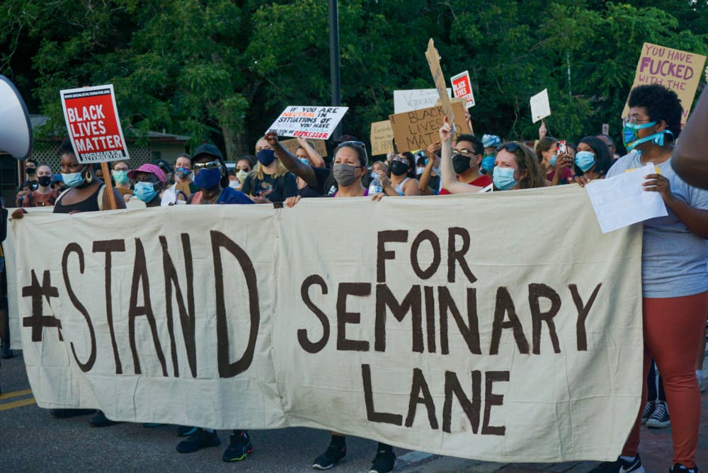 Protesters hold a banner that reads, "#StandForSeminaryLane," demanding that developers refrain from building luxury student apartments on land located in a historically Black community. 