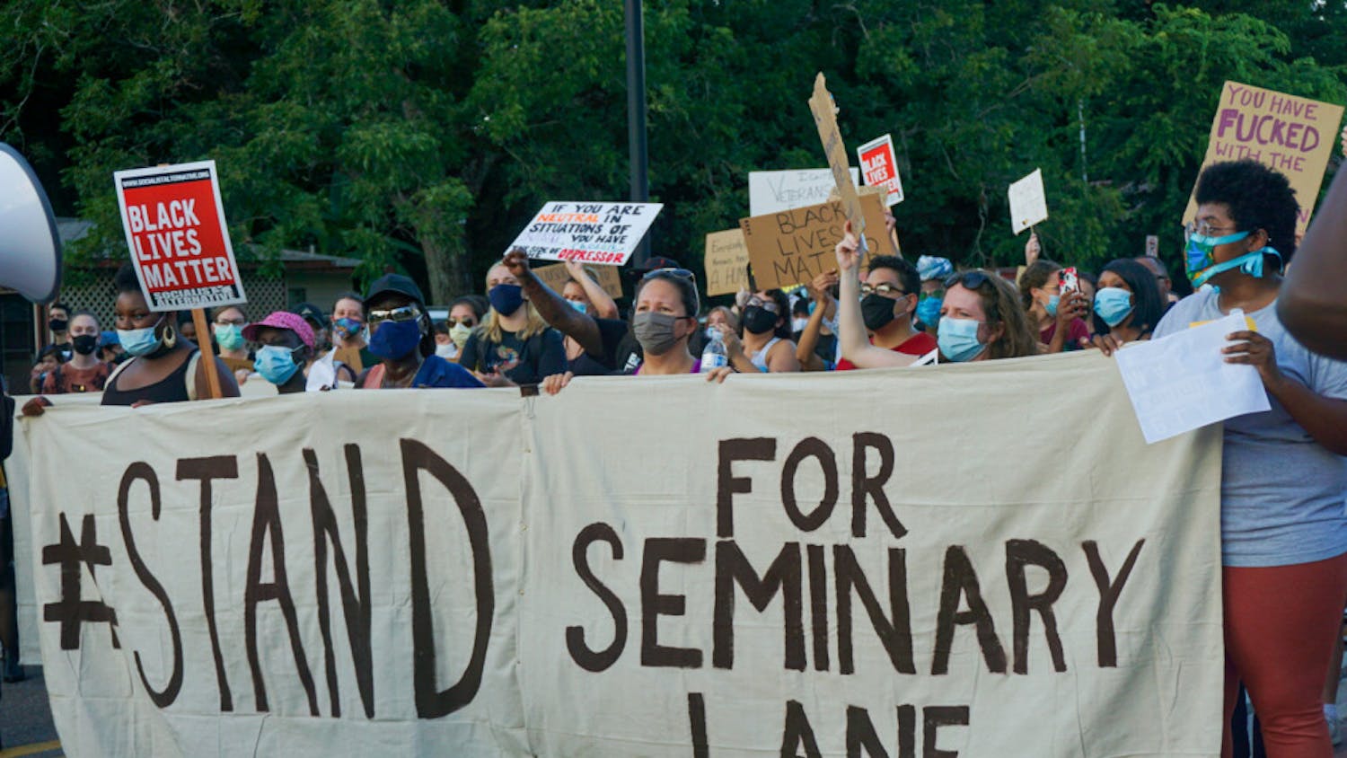 Protesters hold a banner that reads, "#StandForSeminaryLane," demanding that developers refrain from building luxury student apartments on land located in a historically Black community. 